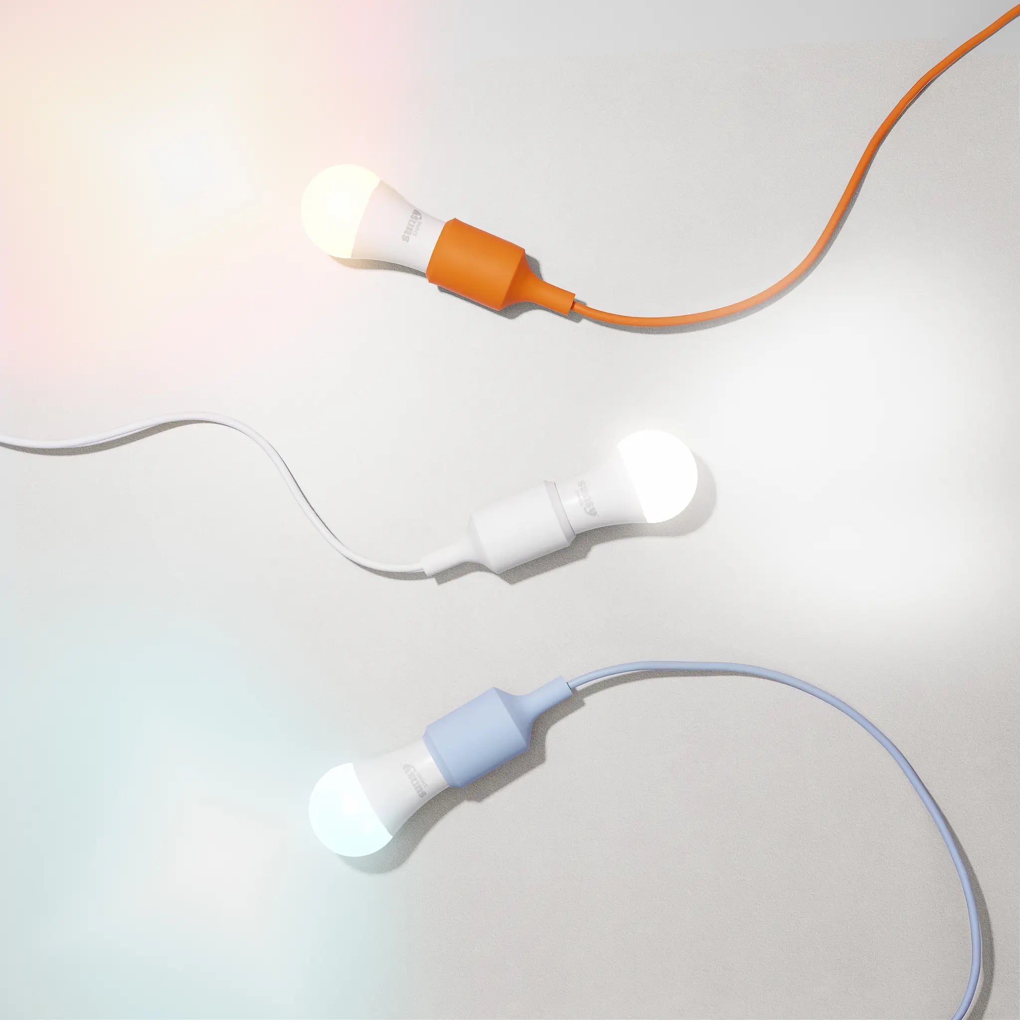 all_three_sunsy_shine_light_bulbs_lit_up_on_a_white_background_shwoing_thier_orange_white_and_blue_color_temperatures